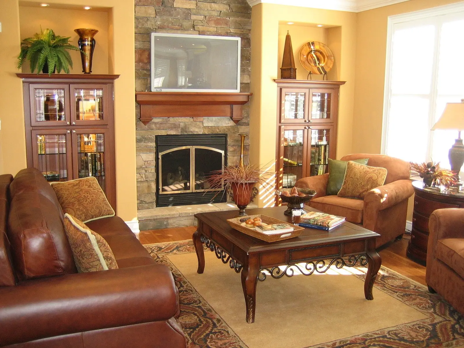 Living room with a stone fireplace, built-in cabinets, and leather sofas