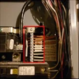 Inspection report photo of an electrical subpanel with the problem area outlined in red